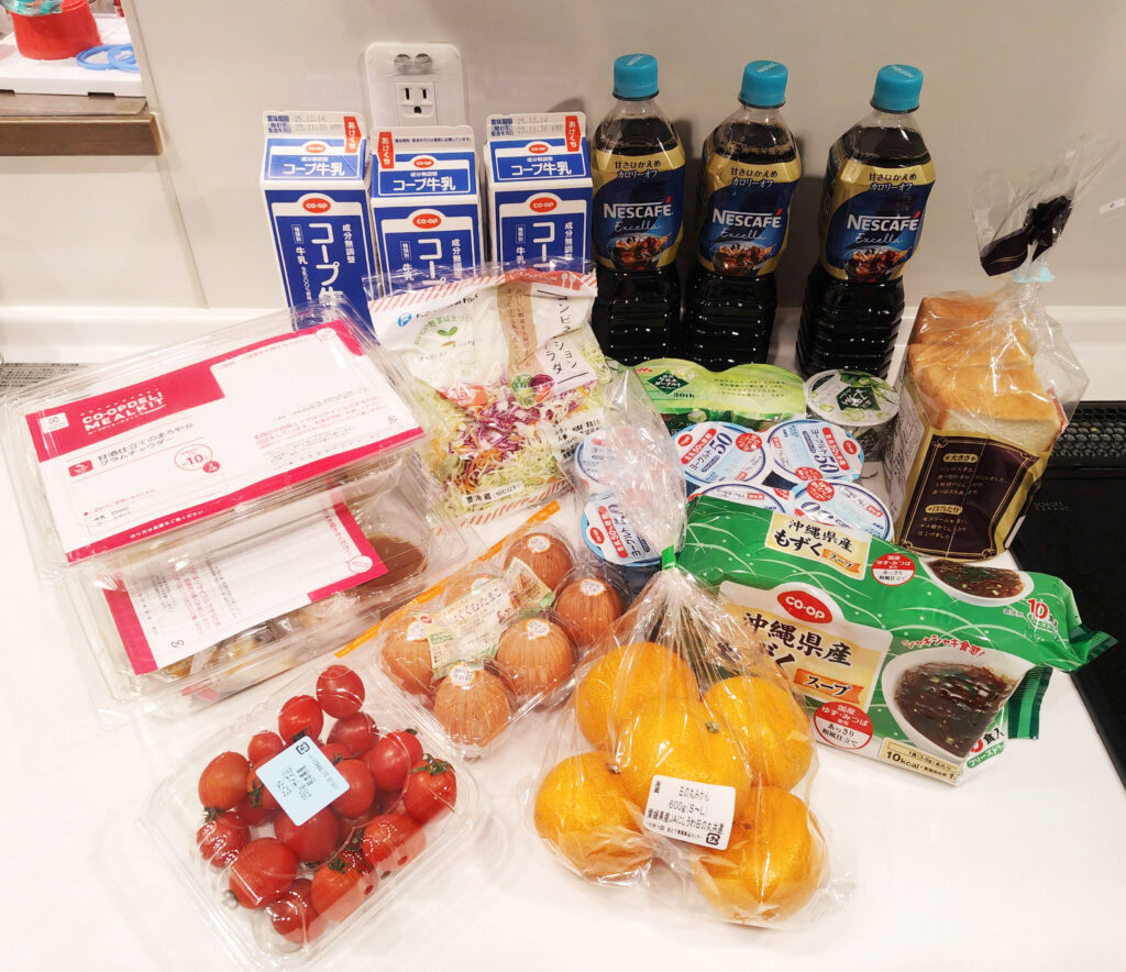 コープデリで届いた牛乳や飲料、パン、野菜、果物などの注文品を並べた様子