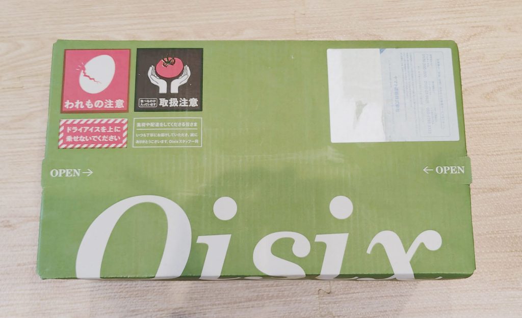 緑色のOisixロゴ入り配送箱を床に置いた写真